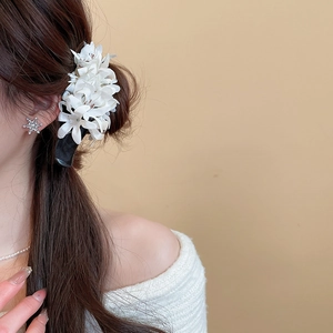 Detail of elegant white fabric flower hair clip worn by a model in a warm setting