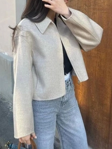 Dettaglio ravvicinato della giacca corta beige con morbida texture ed elementi zip