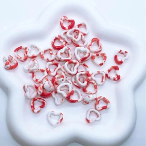 Detailed view of heart-shaped ceramic beads with red marble ink pattern in white tray