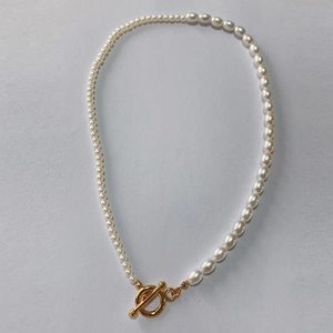 Detail shot of white pearls and golden OT toggle clasp on a bohemian necklace