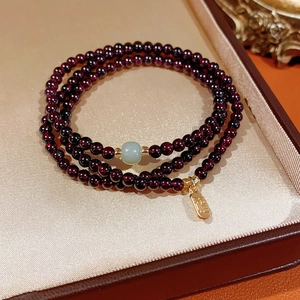 Detailed macro shot of red garnet bead bracelet with golden Fu pendant in premium gift box