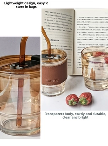 Close-up of glass coffee cup with brown leather sleeve and black lid in a cozy setting