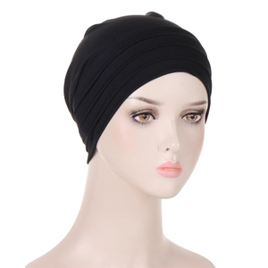 Detail of black pleated turban hat with elastic fabric texture on model head