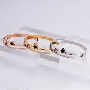 Three stacked star charm bangles in rose gold, gold, and silver finishes with zircon stones
