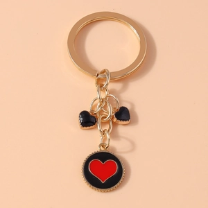 Detail of gold keychain with black and red heart charms and enamel round pendant