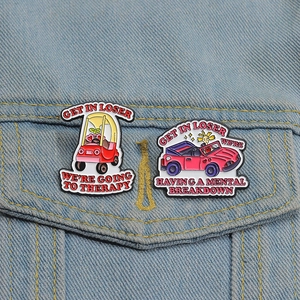 Detail of funny pink enamel car brooches on denim jacket with witty mental health quotes
