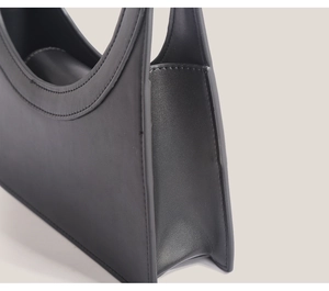 Side view detail of a black leather handbag featuring neat stitching and smooth texture