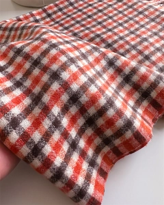 Close-up of orange and brown plaid cashmere-like fabric with thick wool texture