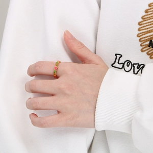 Detail of colorful enamel heart patterns on a gold stainless steel ring worn by a model