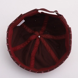 Detail of burgundy cotton docker hat featuring metal adjustment buckle and frayed edges