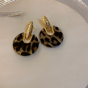 Detail of leopard print resin hoop earrings with hammered gold metal on white tray