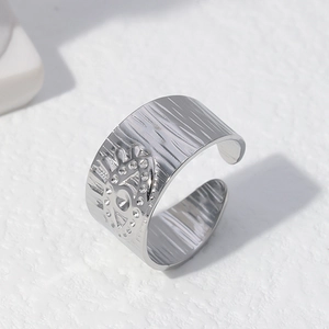 Bague en acier argenté à texture martelée et motif œil soleil sur fond blanc