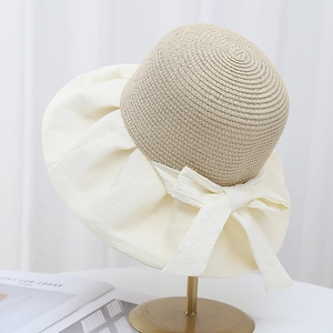 Close-up of elegant straw weave sun hat with cream fabric brim and bow detail