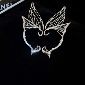 Detail of silver butterfly wing ear cuffs with hollow textures on black velvet