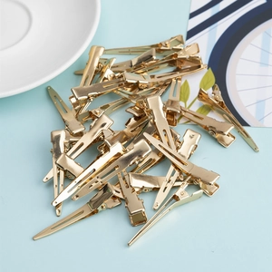 Golden alloy alligator hair clips for DIY hair accessories shown on light blue background