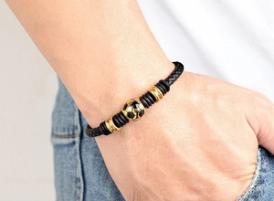 Detail of men's leather bracelet featuring a golden soccer bead and black woven cord