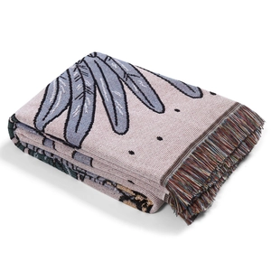 Close-up of bohemian knit throw blanket with blue feather patterns and colorful tassels