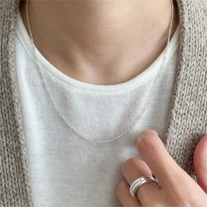 Minimalist 925 sterling silver chain necklace and sleek ring worn on casual outfit