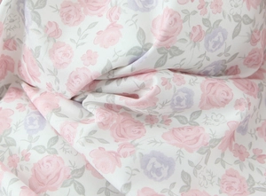 Dettaglio di tessuto bianco con stampa floreale di rose rosa e viola e trama molto fine