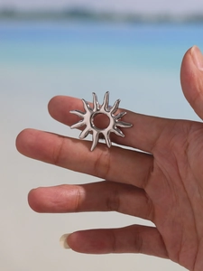 Detail shot of sunbeam adjustable ring in silver finish worn on finger at the beach