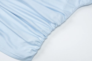 Close-up of light blue ruched mesh fabric texture and fine stitching on a slim-fit skirt