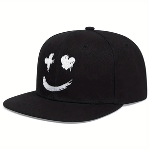 Détail de la broderie blanche sur une casquette noire affichant un motif de visage souriant