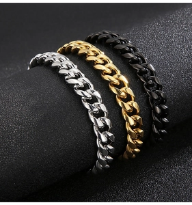 Three Cuban link bracelets in gold, silver, and black metal finishes on a dark display