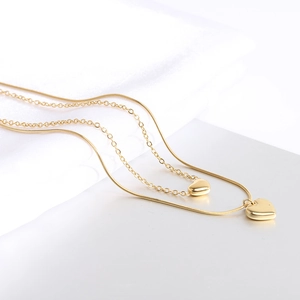 Collana a doppio strato dorata con ciondoli a cuore su seta bianca per un look chic