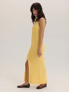 Détail de la robe en maille jaune avec patte de boutonnage et fente latérale chic