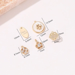 Detailansicht von fünf goldenen DIY-Schmuckanhängern mit Zirkonia-Blumen und Glücksbringern