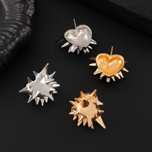 Macro shot of punk heart-shaped earrings with spikes in gold and silver finish