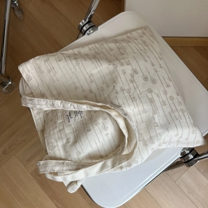 Detail of cream canvas tote bag with vertical botanical pattern and fabric woven label