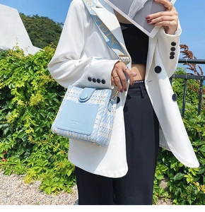 Close-up of light blue tweed crossbody bag with wide jacquard strap and gold hardware