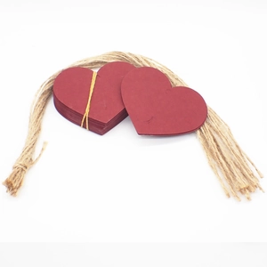 Close-up of red heart-shaped kraft paper gift tags with natural jute twine on white background