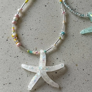 Macro detail of iridescent resin starfish pendant and colorful handmade beads