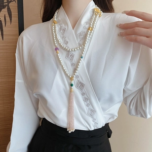 Detail of multi-layer pearl body chain with lotus charm and pink crystal tassel