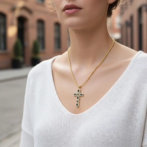 Nahaufnahme der goldenen Kordelkette mit blauem Saphirkreuz und Mikro-Diamantbesatz