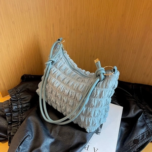 Dettaglio borsa azzurra con texture a bolle e anelli in metallo dorato sulla tracolla