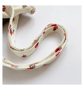Detail showing white corduroy strap with cute red strawberry print on tote bag