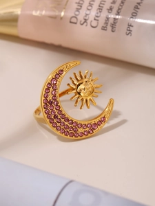 Close-up of 18K gold sun and moon ring with pink zircon inlay on light surface
