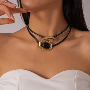 Détail d'un pendentif spirale doré avec pierre noire sur un collier ras du cou double