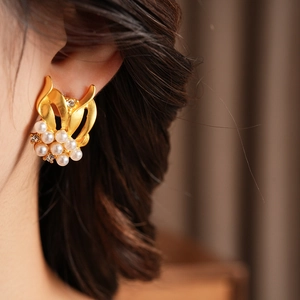 Close-up of vintage gold leaf earrings with white pearls and sparkling zircon on model