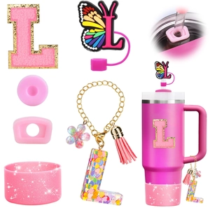 Close-up of pink glitter letter L charm and resin butterfly straw cover accessories