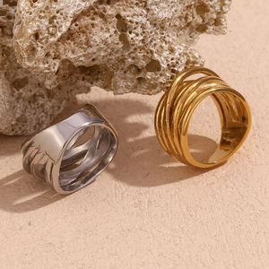 Detailed view of layered woven rings in silver and gold finish on beige stone
