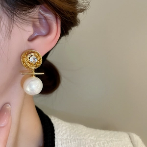 Gros plan d'élégantes boucles d'oreilles perles plaquées or avec zircon sur l'oreille