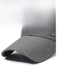 Detail view of the long brim and small metal FASHION logo on a grey men's baseball cap