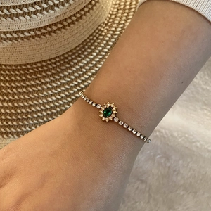 Détail d'un bracelet en or avec zircon vert émeraude porté sur le poignet d'un mannequin