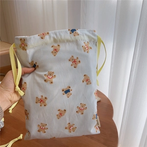 Detail of blue striped cotton drawstring bag with bear print and yellow cord closure