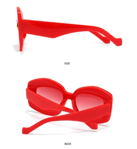 Detail view of red irregular polygon sunglasses with gold round hinge accents on white background