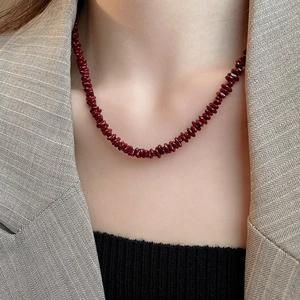 Close-up of vintage dark red irregular stone beaded necklace on a stylish blazer outfit